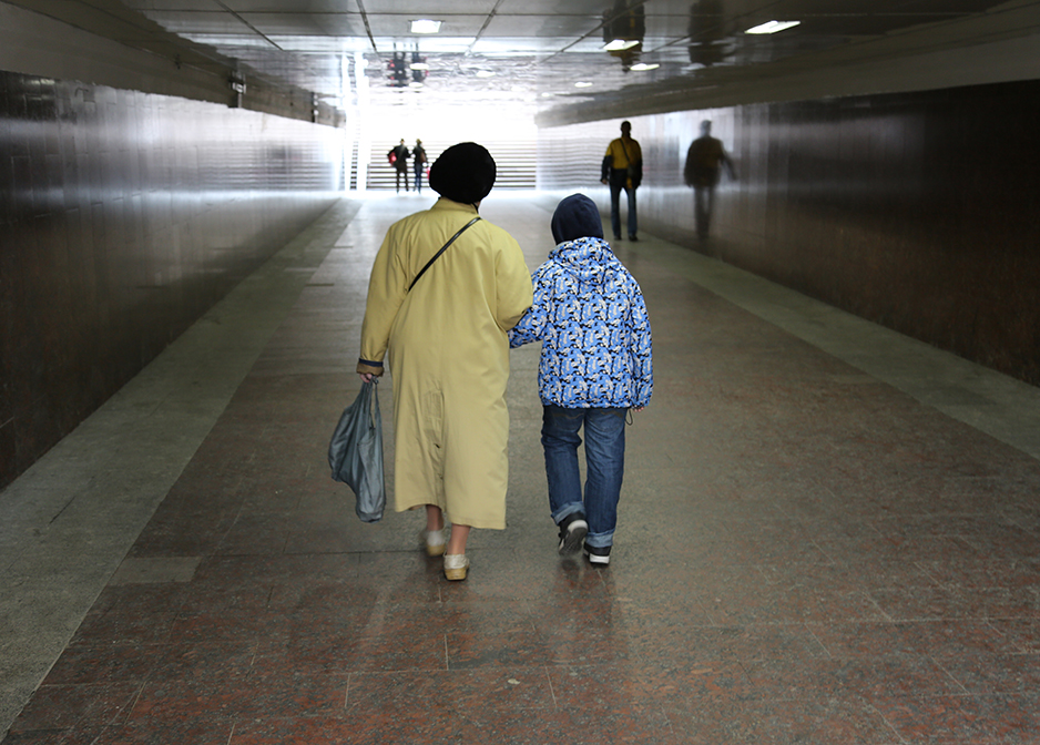 a child walks with an older lady in the entrance to the subway in Moscow