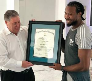 President DeCenzo presents Josh Norman with the honorary docterate of public service.