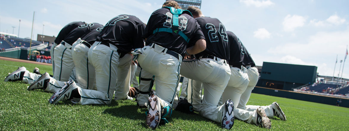 The baseball team kneeling on baseball field