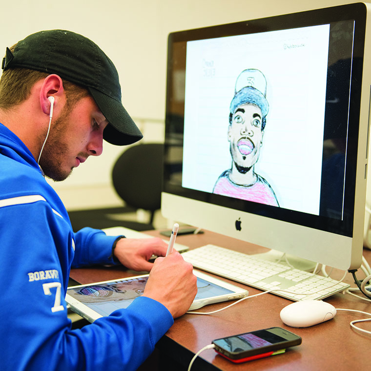 Student working between iPad and mac in Edwards Design Studio