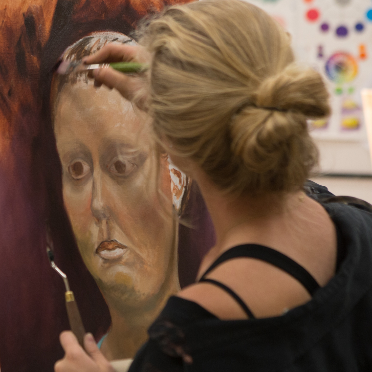 Student painting portrait in painting studio.