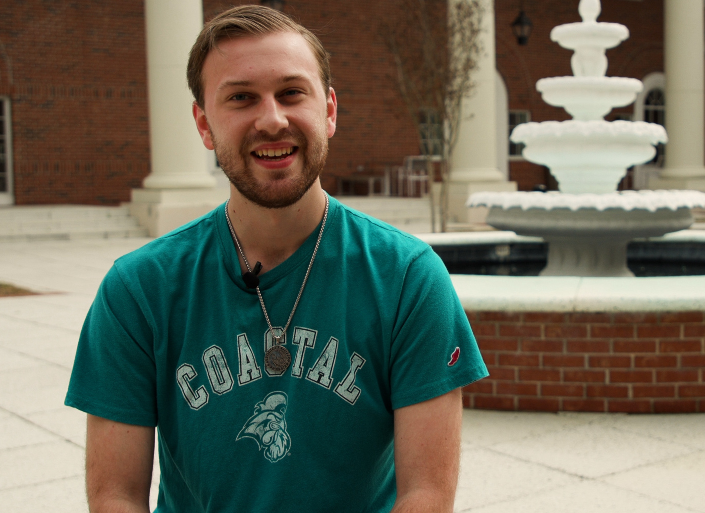 Tyler Hancock, a philosophy major, sits in the Edwards Courtyard. The fountain is visible behind him.
