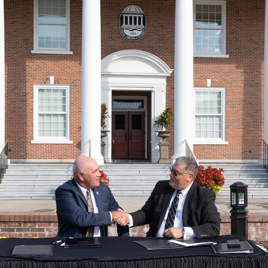 Tim Hardee and President David A. DeCenzo shake hands after signing the agreement.